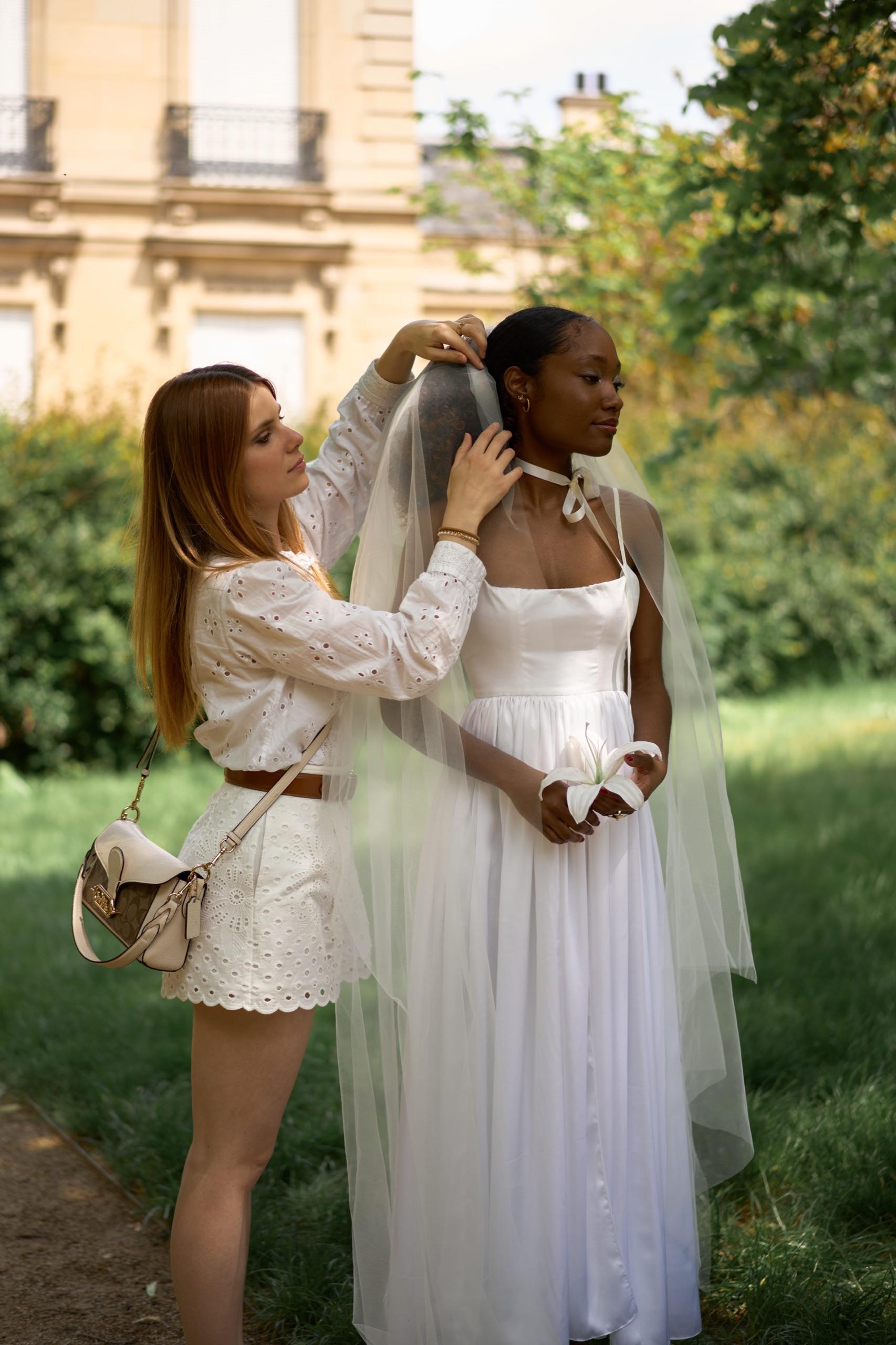 Une couturière partenaire ajustant le voile d'une mariée lors d'un essayage