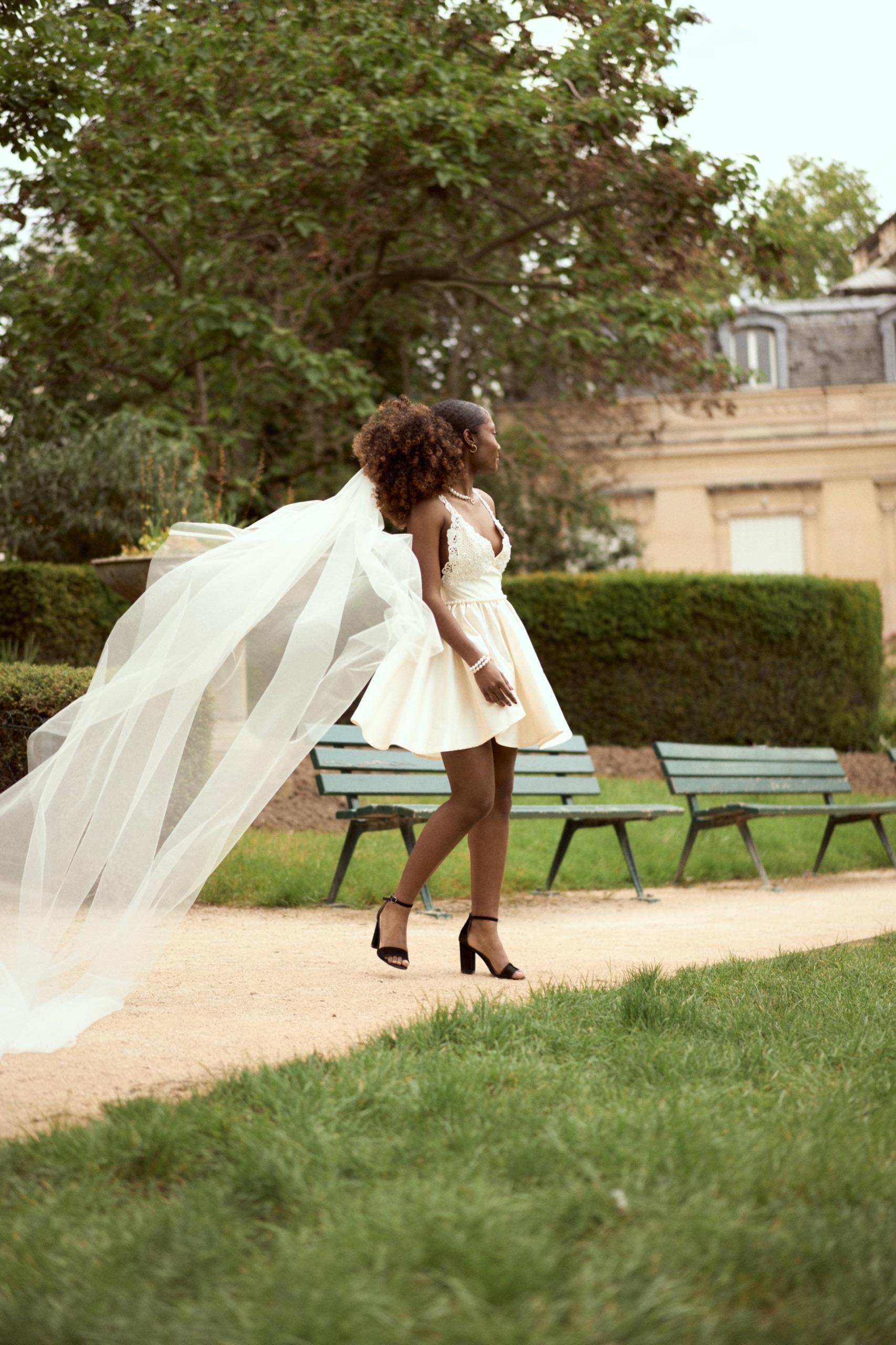 Manon marchant dans un jardin parisien, voile porté par le vent